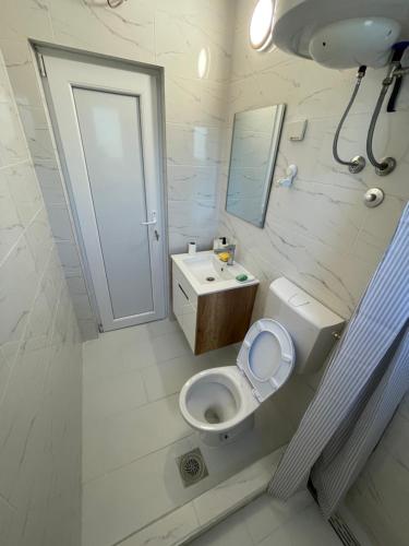 a white bathroom with a toilet and a sink at Deda Momirov zavičaj in Tulež