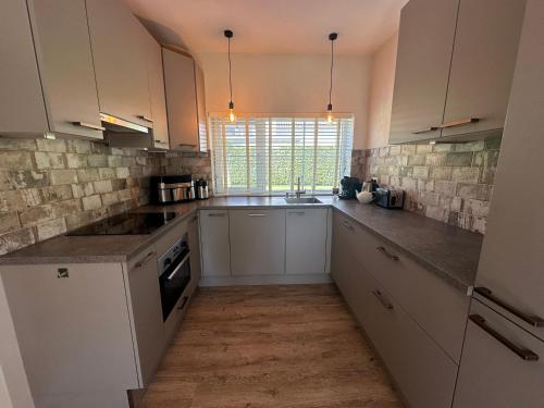 a large kitchen with white cabinets and a window at Vakantieverblijf De Hoge Boekel in Enschede