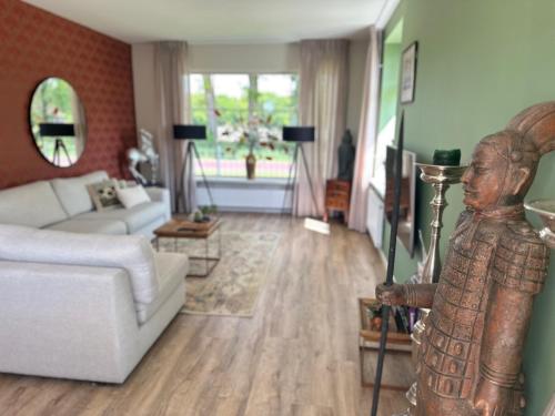 a living room with a couch and a statue in the foreground at Vakantieverblijf De Hoge Boekel in Enschede