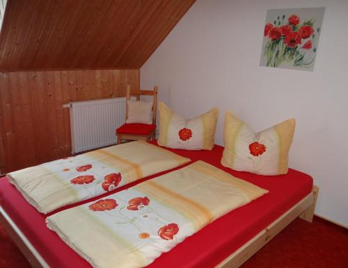 una camera da letto con letto con lenzuola e cuscini rossi di Fewo zwischen München und Garmisch a Wielenbach