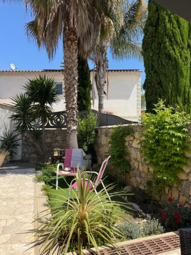 a patio with a pink chair and palm trees at chez Maël in Le Muy