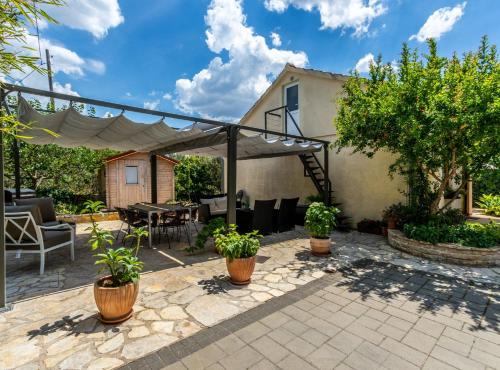 a patio with potted plants and a tent at Holiday Home Regina in Brodarica