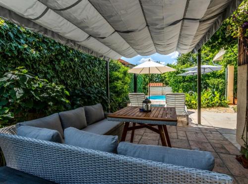 a patio with a couch and a table with an umbrella at Holiday Home Regina in Brodarica