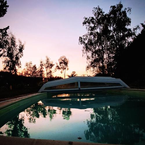 un bassin d'eau avec des arbres en arrière-plan dans l'établissement Gîte avec piscine, à Pezou