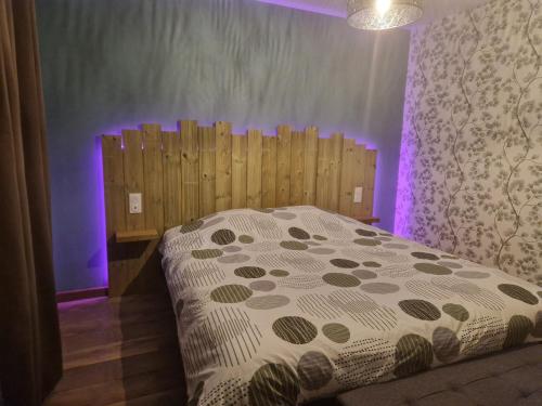 a bedroom with a bed with a wooden head board at Un Moment Spa - le Gaïa in Sailly-sur-la-Lys