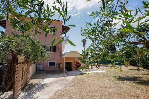 an exterior view of a pink house with trees at Iris Apartments in Glyfada