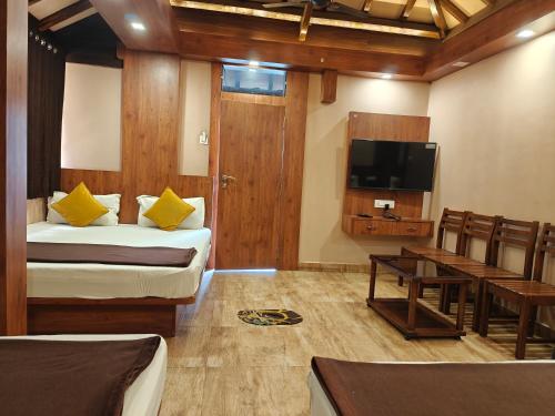 a room with two beds and a flat screen tv at Prime Residency in Kolhapur