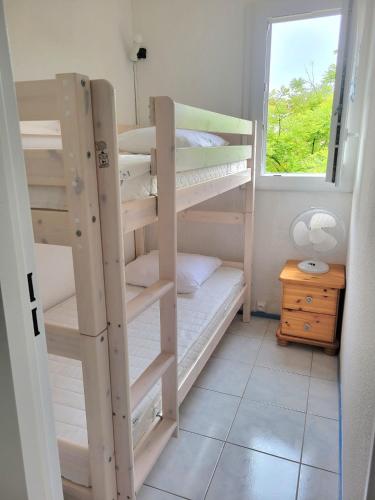Cette chambre comprend 2 lits superposés et une fenêtre. dans l'établissement Grand studio cabine 4 personnes Clim Très bien situé, au Cap d'Agde