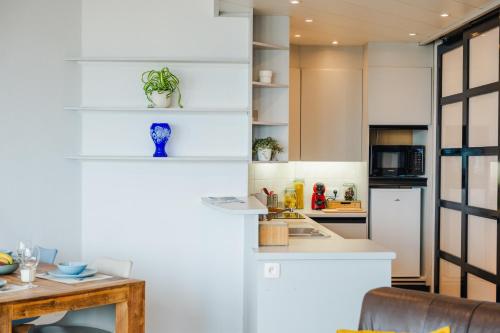 a kitchen with white cabinets and a table at Apartment - frontal sea view in Ostend