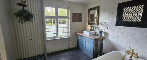 Le Petit Paradis في روبرتسون: حمام مع حوض ومغسلة ونافذة