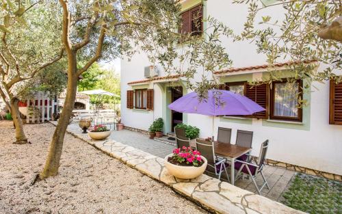 a patio with a table and a purple umbrella at Apartments Frgacic in Baška
