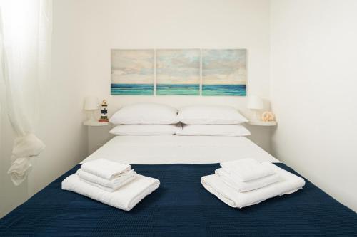 Una cama blanca con toallas encima. en AlMarè Home, en Torre Canne