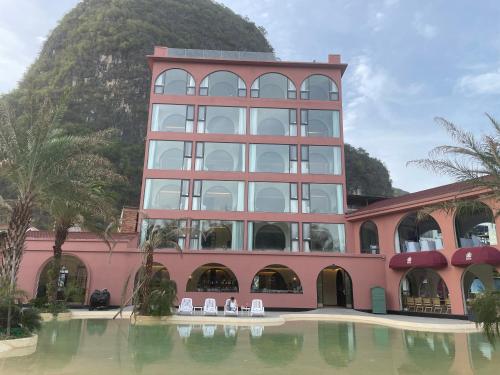 a pink building with chairs in the water in front at Norton Manor Yangshuo in Yangshuo