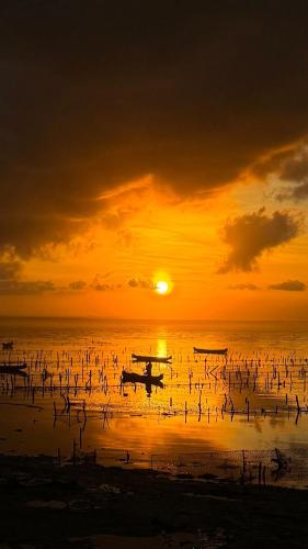 a sunset over the ocean with boats in the water at Double'A beach house in Nusa Lembongan