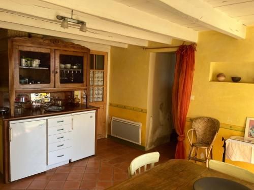 une cuisine avec des armoires blanches et une table dans une pièce dans l'établissement La Maison de la Treille, à La Chapelle-Montbrandeix