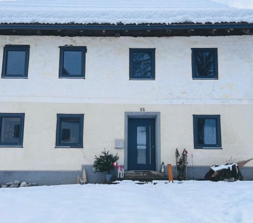 a white building with blue doors in the snow at Binter Haus -Rattendorf in Rattendorf