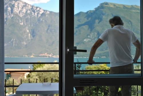 a man standing on a balcony looking out the window at Hotel Villa Grazia in Limone sul Garda