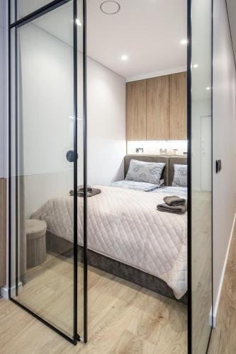 a bedroom with a bed and a glass wall at Sea Whisper apartamentai Daukanto g Palanga in Palanga