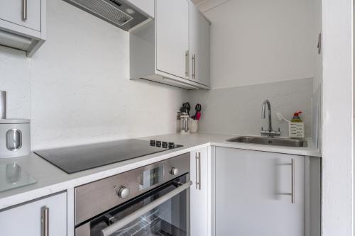 a kitchen with white cabinets and a sink at Belmont Apartment in Belfast