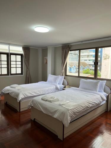 two beds in a bedroom with two windows at Urban Grace in Bangkok