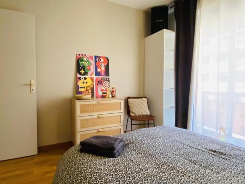une chambre avec un lit, une commode et une chaise dans l'établissement LE St LAURENT, à Rodez