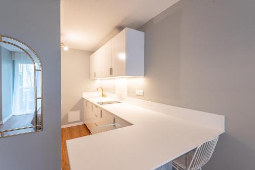 - une cuisine blanche avec un évier et un miroir dans l'établissement M40 Joli studio au calme, à Annemasse