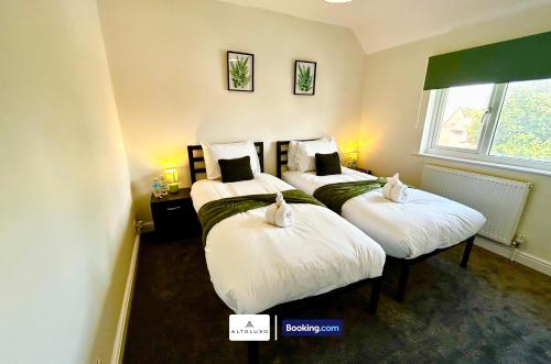 two beds in a hotel room with a window at The Jungle Comfy & Spacious 3BR by AltoLuxo Short Lets & Serviced Accommodation With Free WiFi & Parking in Bristol