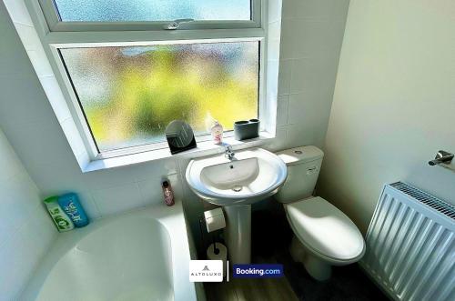 a bathroom with a sink and a toilet and a window at The Jungle Comfy & Spacious 3BR by AltoLuxo Short Lets & Serviced Accommodation With Free WiFi & Parking in Bristol