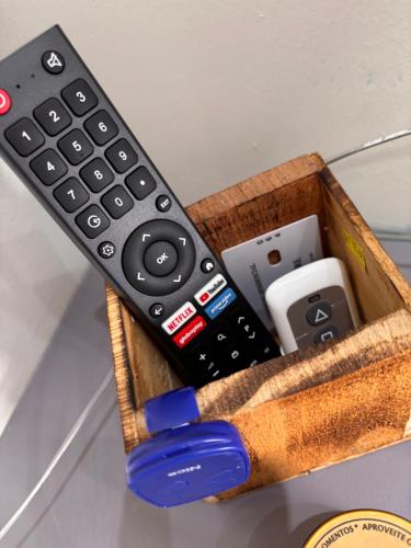 a remote control and other electronics in a wooden holder at Studio Home 64 Luxo in Mogi das Cruzes