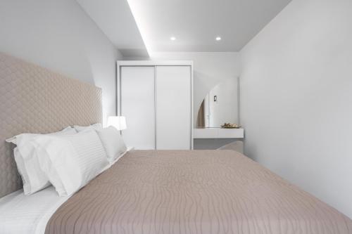 a white bedroom with a large bed with white pillows at studios ioanna in Vourvourou