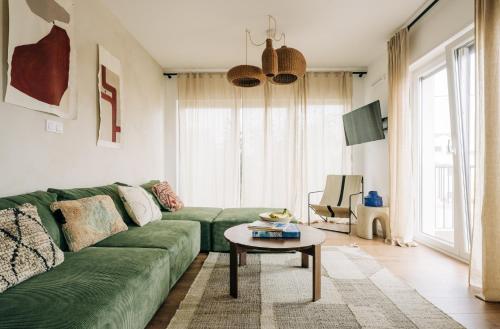 a living room with a green couch and a table at Octopus House Caparica in Costa da Caparica