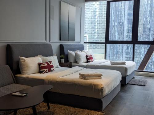 Un dormitorio con dos camas y un sofá y ventanas. en Scarletz Suites KLCC by Classic, en Gua Sai