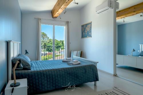 une chambre avec un lit et une grande fenêtre dans l'établissement Villa des Chardonnerets, à Mougins