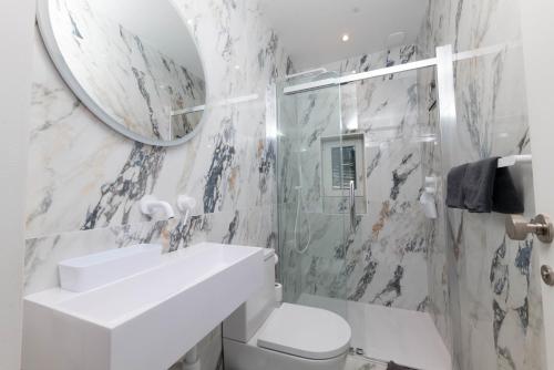 une salle de bain blanche avec un lavabo et un miroir dans l'établissement Villa Illette Cap d Antibes, à Antibes