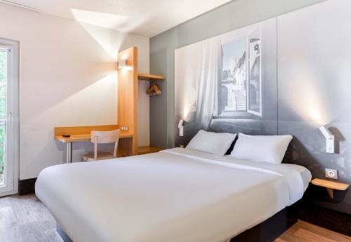 a bedroom with a large white bed and a desk at B&B HOTEL Narbonne 1 in Narbonne
