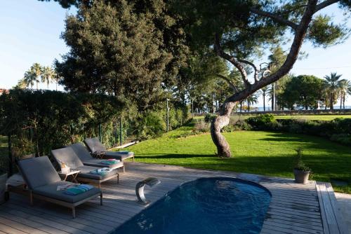 - une piscine avec 2 chaises longues et un arbre dans l'établissement Villa Illette Cap d Antibes, à Antibes
