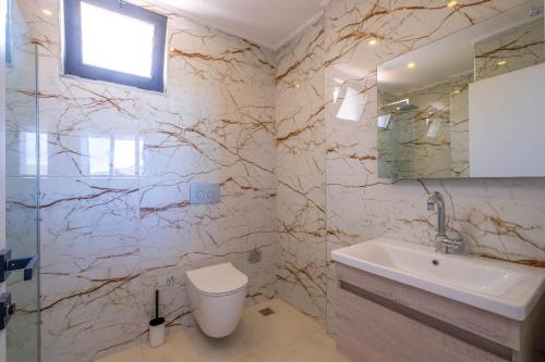 a bathroom with a sink and a toilet and a mirror at VillA Ari in Kas
