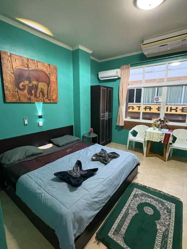 a bedroom with a large bed with blue walls at San Antonio Beach Guesthouse & Restaurant in Kata Beach