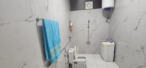 a bathroom with a toilet and a blue towel at العييري للشقق المخدومة الباحة 4 in Al Baha