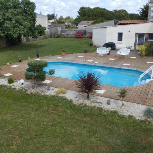 - une piscine dans une cour avec une terrasse en bois dans l'établissement maison de vacances de 16 a 22 personnes, à Gémozac