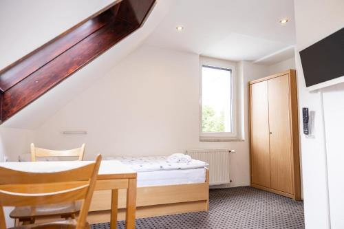 a bedroom with a bed and a table and a window at Pension Märkl Augsburg in Augsburg
