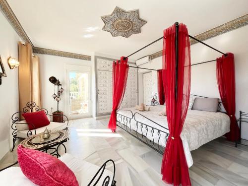 a bedroom with a canopy bed with red curtains at Villa Aurelia Sea views Heatable Pool - Billiard Ping-pong Fooball table - Beach & All at 500 m in La Cala de Mijas