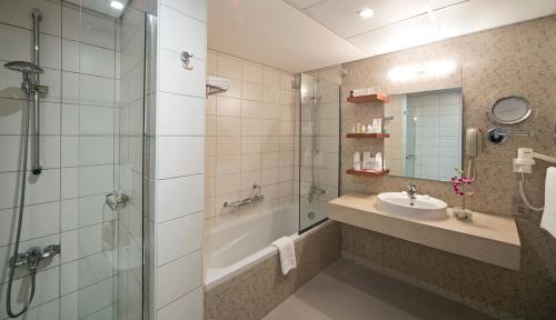 a bathroom with a shower and a sink and a tub at City Seasons Al Hamra Hotel in Abu Dhabi