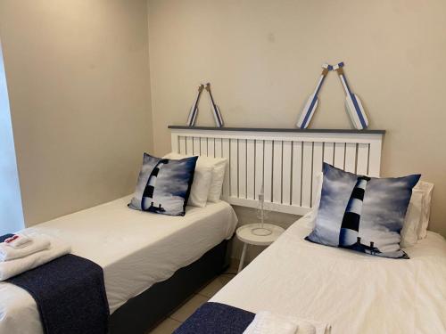 a bedroom with two beds with blue and white pillows at Salt & Cellar - Paarl - Self Catering Apartment in Paarl