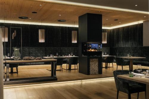 a restaurant with tables and chairs and a fireplace at Sportresidenz Zillertal - 4 Sterne Superior in Uderns