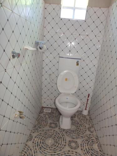a bathroom with a toilet in a tiled room at VINTEX GUEST HOUSE in Kimana