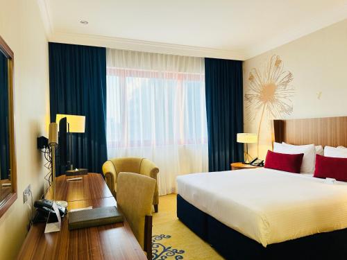 a hotel room with a large bed and a desk at City Seasons Al Hamra Hotel in Abu Dhabi