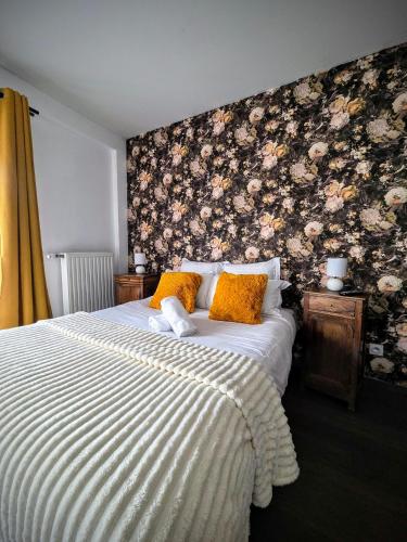 a bedroom with a bed with a floral wall at Le Clos des Roses in Pérouges