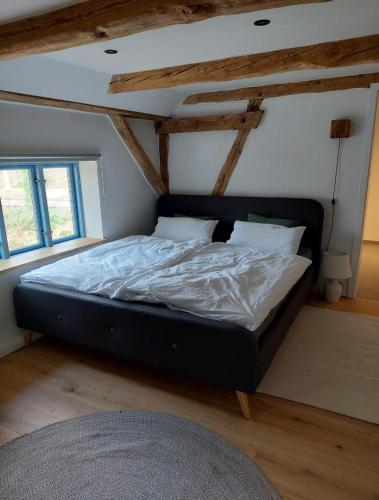 a large bed in a room with wooden ceilings at ALTE SCHEUNE Ferienwohnungen - Wohnung 4 in Suderburg