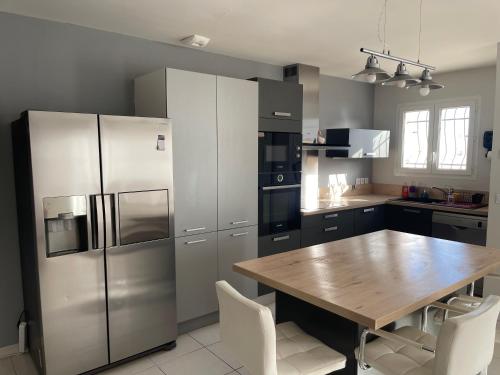La cuisine est équipée d'une table en bois et d'un réfrigérateur en acier inoxydable. dans l'établissement Villa calme deux chambres proche de la mer tout confort, à Pinet